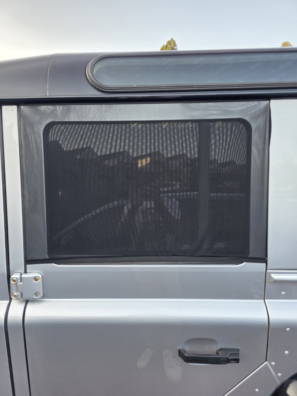 Sun shade sock fitted to the rear side window of a Land Rover Defender